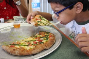 Eshaan eating pizza from Pure Pizza at 7th st public market
