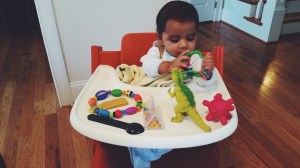 Day at the office - Arjun sitting in high chair and playing with his toys